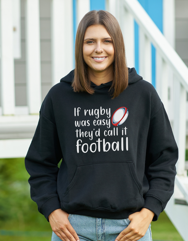 Woman wearing a black hoodie with rugby-themed text and design with a Cows Corner slogan saying if rugby was easy they'd call if football