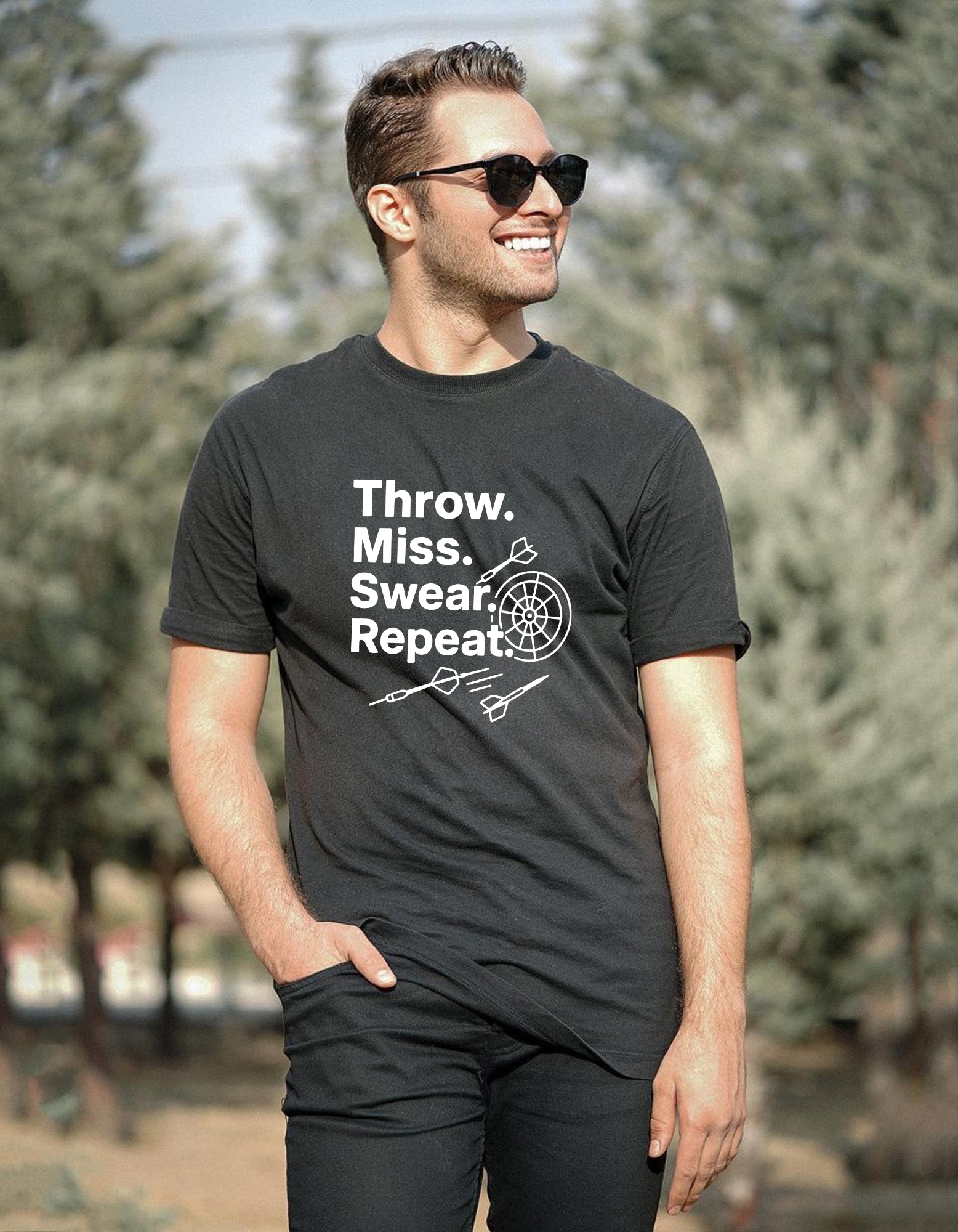 Man wearing a black t-shirt with text and graphics outdoors with a Cows Corner slogan saying Throw, Miss, Swear, Repeat.