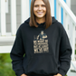 Person wearing a black hoodie with a graphic and text, standing outdoors, with slogan on the front saying 'We Might Be the Underdogs, but at Least We’ve Got Better Teeth – Scott Gibbs