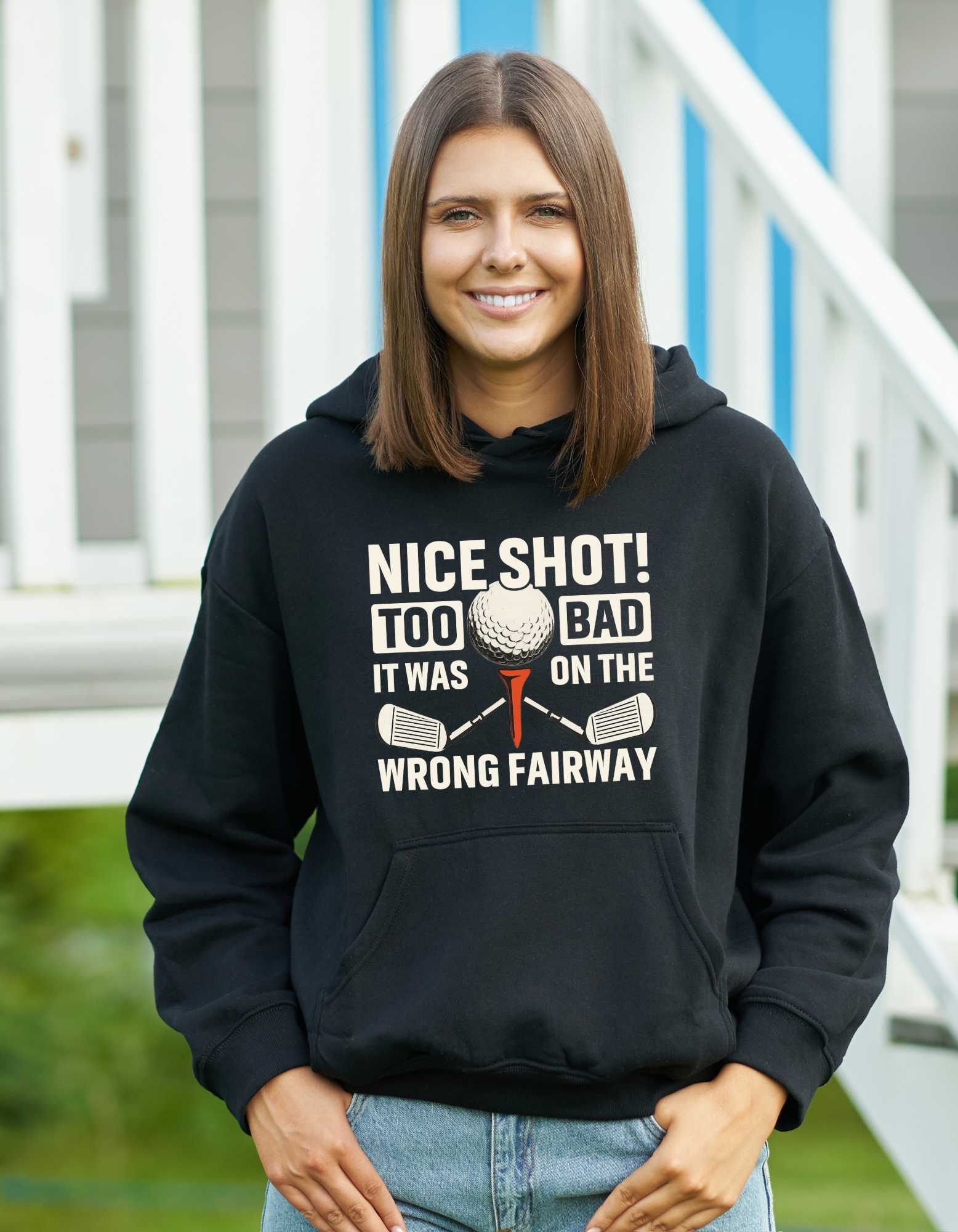Woman wearing a black hoodie with a golf-themed design, standing outdoors.