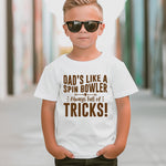 A little boy wearing a white t-shirt with Funny Cricket T-Shirt – "Dad’s Like a Spin Bowler, Always Full of Tricks!" on the front. A funny T-shirt, Premium Fabric, Multiple Junior Sizes, Perfect for Boys and Girls