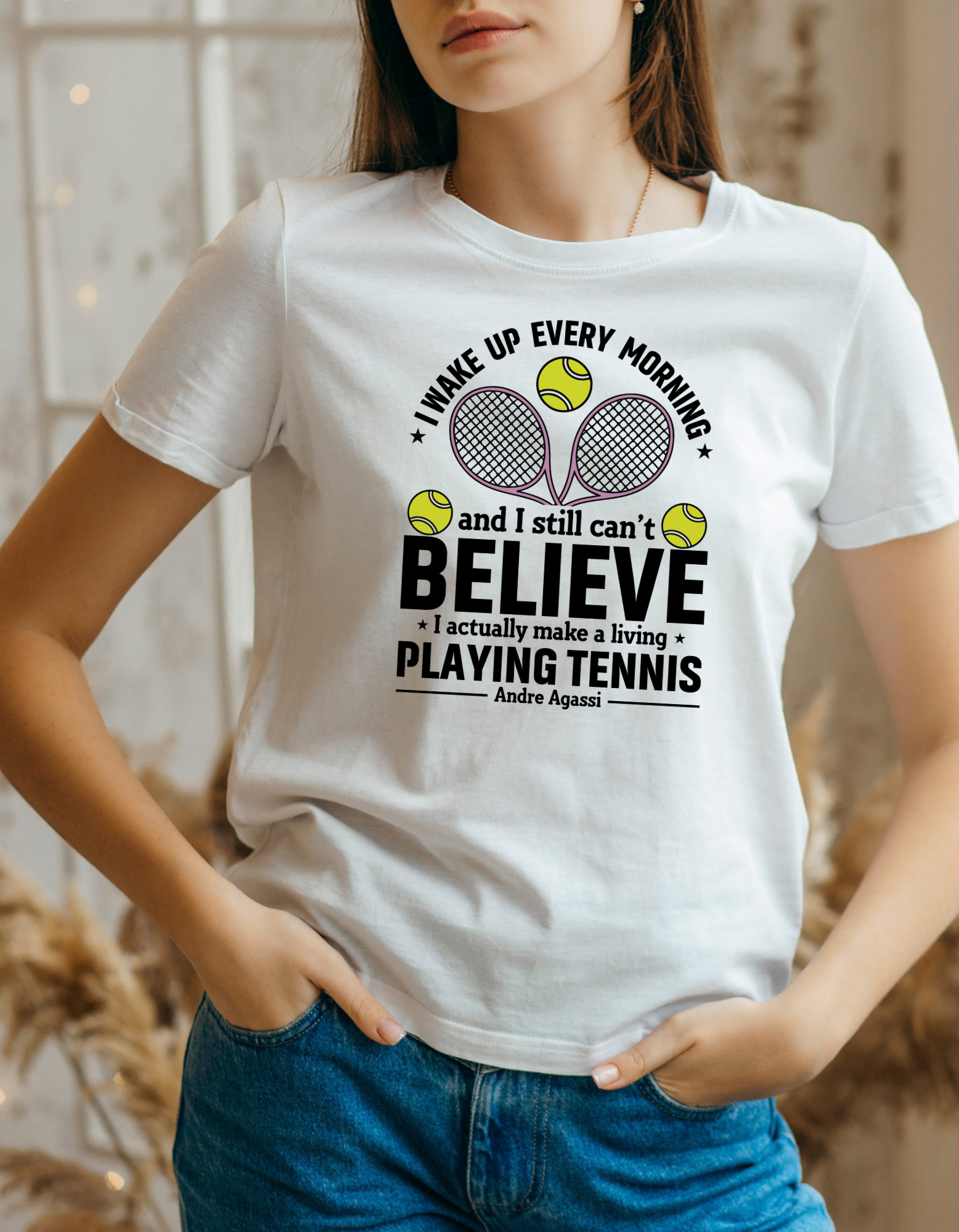 A lady wearing a white t-shirt with funny tennis slogan on the front that reads 'A white ceramic mug with tennis slogan on the front that reads 'I Wake Up Every Morning and Still Can’t Believe I Actually Make a Living Playing Tennis.'
