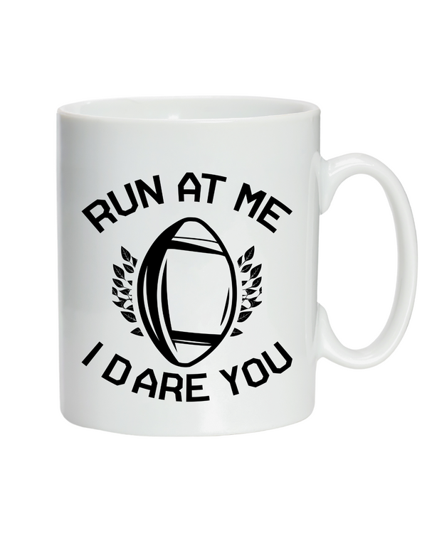 White mug with black text and rugby ball design on a white background with a Cows Corner slogan saying run at me I dare you