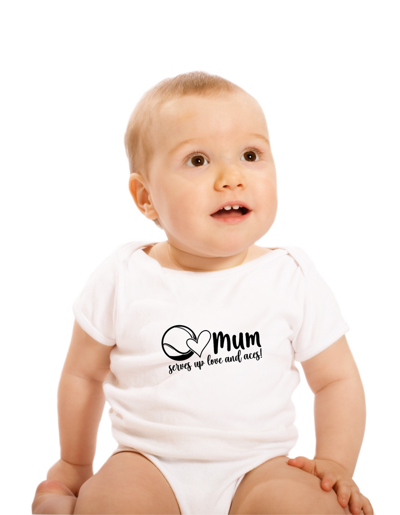 A little baby wearing a white baby grow with tennis slogan on the front that reads 'Mum Serves Up Love and Aces'.