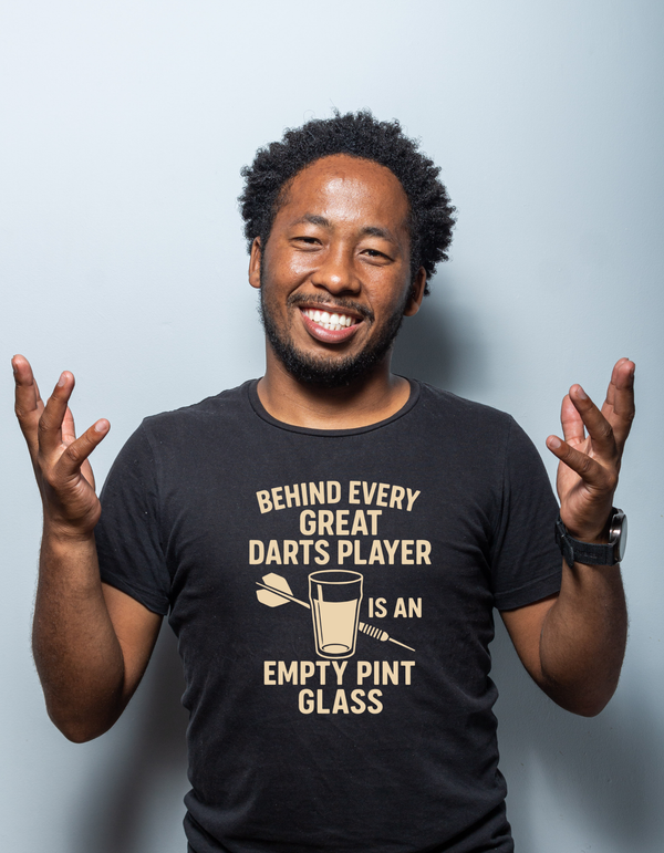 Man wearing a black t-shirt with a humorous dart player quote on a light gray background with a Cows Corner slogan saying Behind every great darts player is an empty pint glass