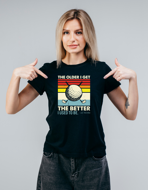 Woman wearing a black t-shirt with a graphic and text, pointing at the shirt with a Cows Corner slogan saying The older I get, the better I used to be - Lee Trevino