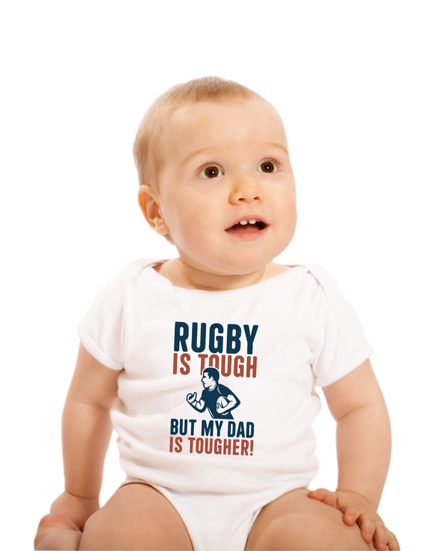 Baby wearing a white onesie with 'Rugby is tough, but my dad is tougher!' text with a Cows Corner slogan saying Rugby is tough, but my dad is tougher