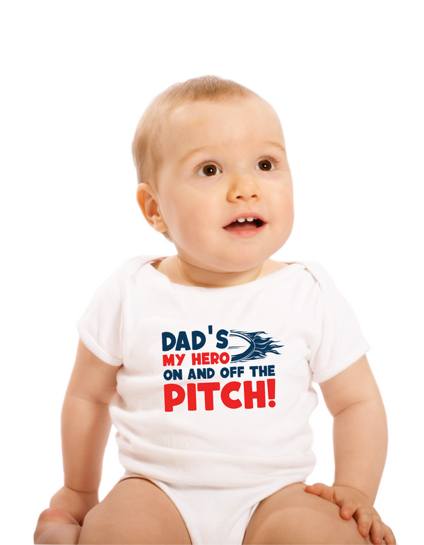 Baby wearing a white onesie with text on a white background with the Cows Corner slogan saying Dad's my hero on and off the pitch