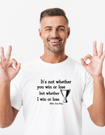A man wearing a white t-shirt with the funny tennis slogan on the front reading 'It’s Not Whether You Win or Lose but Whether I Win or Lose – Billie Jean-King!