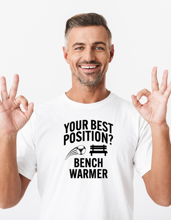 A man wearing a white t-shirt that has the funny football slogan on the front that reads 'Your Best Position? Bench Warmer'