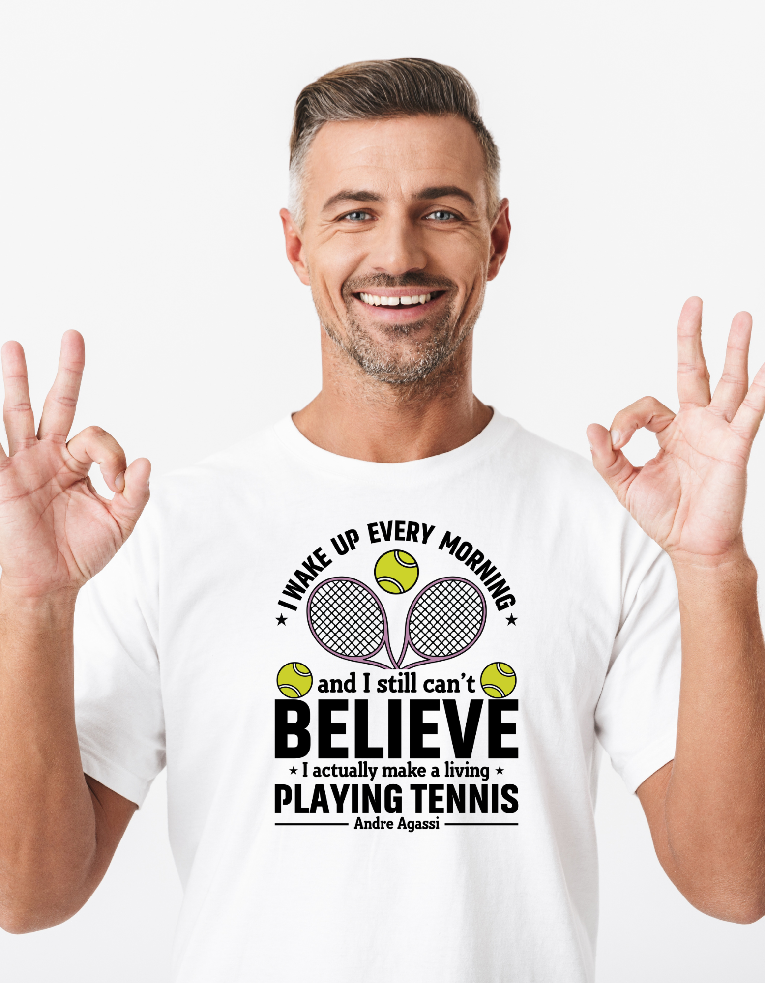 A man wearing a white t-shirt with funny tennis slogan on the front that reads 'A white ceramic mug with tennis slogan on the front that reads 'I Wake Up Every Morning and Still Can’t Believe I Actually Make a Living Playing Tennis.'
