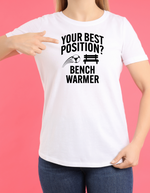 A lady wearing a white t-shirt that has the funny football slogan on the front that reads 'Your Best Position? Bench Warmer'