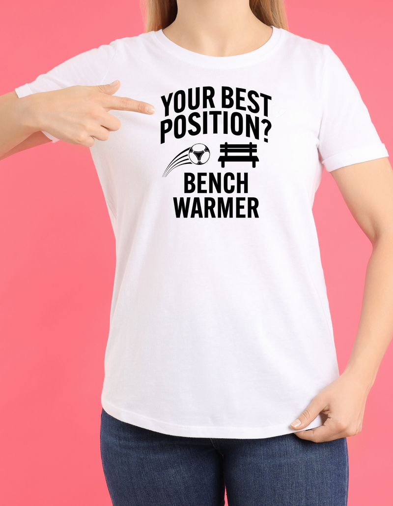 A lady wearing a white t-shirt that has the funny football slogan on the front that reads 'Your Best Position? Bench Warmer'