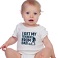 A little baby wearing a baby grow with the funny football slogan on the front saying 'I Get My Tekkers From Dad'