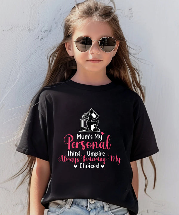 A little girl wearing a black t-shirt with Mum's My Personal Third Umpire, Always Reviewing My Choices on the front of the T-Shirt. Funny Cricket T-Shirt, Premium Fabric, Multiple Adult Sizes