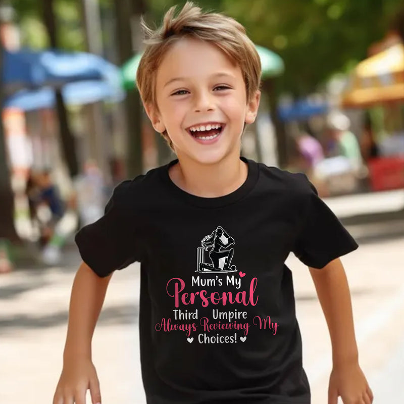 A little boy wearing a black t-shirt with Mum's My Personal Third Umpire, Always Reviewing My Choices on the front of the T-Shirt. Funny Cricket T-Shirt, Premium Fabric, Multiple Adult Sizes