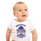 A little baby wearing a white baby grow with the funny football saying that says I love my dad 'Born To Play Football. Raised by a Football Dad!'
