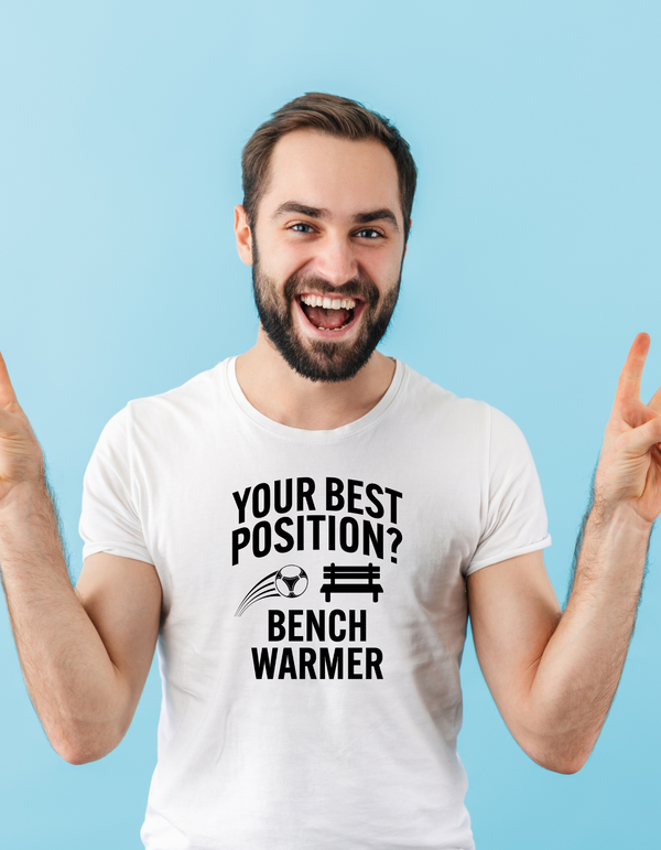 A man wearing a white t-shirt that has the funny football slogan on the front that reads 'Your Best Position? Bench Warmer'