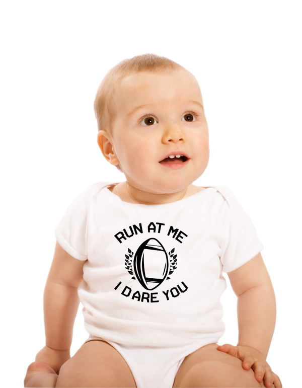 Baby wearing a white onesie with text and a football graphic on a white background with a Cows Corner slogan saying run at me I dare you
