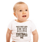 A baby wearing a white baby grow with the funny football slogan on the front saying 'Dad’s First Love: Football. Dad’s Second Love: Me'