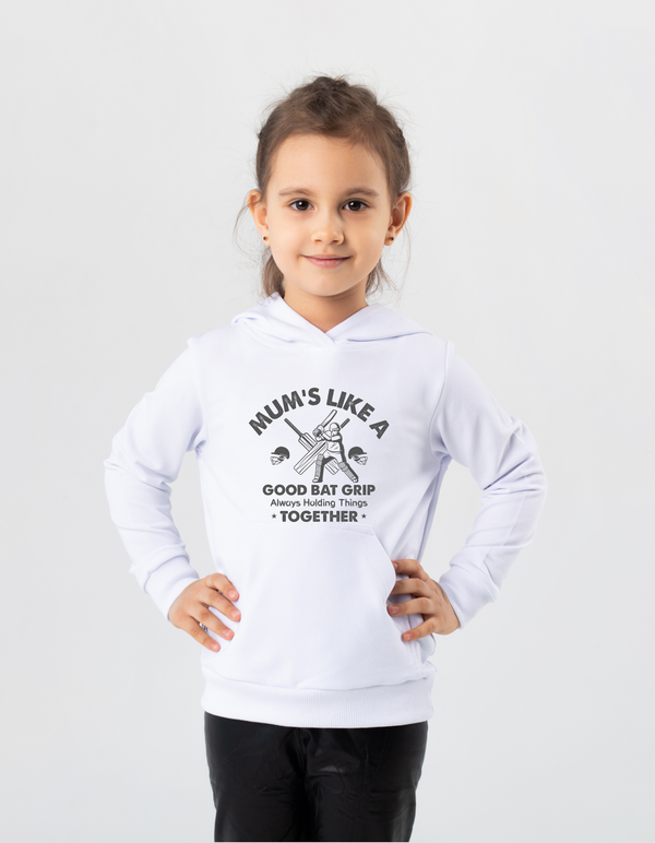 A little girl wearing a white hoodie with Mums Like A Good Bat Grip, Always Holding Things Together on the front. A Funny Cricket T-Shirt, Premium Fabric, Multiple Junior Sizes, Perfect for Boys and Girls