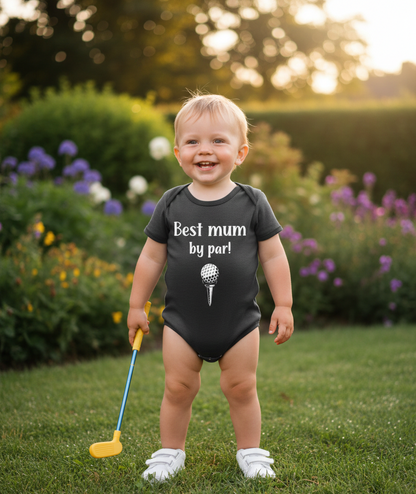 Child wearing a black onesie with text, holding a golf club in a garden setting. The baby is wearing a Cows Corner baby grow with the funny golf slogan 'Best Mum by Par'. Cows Corner gifts are perfect for sport-mad fans, these gifts work brilliantly for birthdays, new baby celebrations, Father’s Day, Mother’s Day, Christmas, anniversaries, thank you gifts, end-of-season team awards, graduations, retirements, and just-because moments when you want to raise a smile. 
