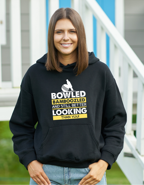 A lady wearing a black hoodie with Bowled & Bamboozled And Still Looking Better Than You on the front, A Funny Hoodie.  Funny Cricket Hoodie, Premium Fabric, Multiple Adult Sizes