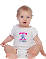 A baby wearing a baby grow with Bowled Over by Mums Love and Cooking, on the front – Funny Cricket Baby Bodysuit, Organic or In-Conversion to Organic Cotton, Self Fabric Bound Neckline, Cuffs and Leg Openings.