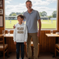 Man and child standing in a room with a view of a sports field outside a large window. The boy is wearing a Cows Corner hoodie with the funny cricket slogan 'Dad’s Like a Spin Bowler, Always Full of Tricks!'. Cows Corner gifts are perfect for sport-mad fans, these gifts work brilliantly for birthdays, new baby celebrations, Father’s Day, Mother’s Day, Christmas, anniversaries, thank you gifts, end-of-season team awards, graduations, retirements, and just-because moments when you want to raise a smile. 

