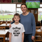 Woman and child in a sports bar with a TV showing a football match.  The boy is wearing a Cows Corner T-shirt with the funny and sweet football slogan on the front that reads 'Football Is Life but Mum Is the Real Boss'.  Cows Corner gifts are perfect for sport-mad fans, these gifts work brilliantly for birthdays, new baby celebrations, Father’s Day, Mother’s Day, Christmas, anniversaries, thank you gifts, end-of-season team awards, graduations, retirements, and just-because moments when you want to 