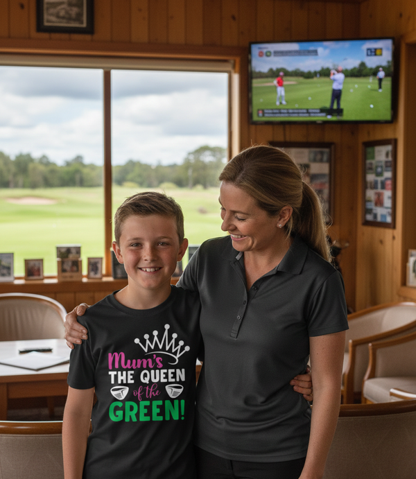 Woman and young boy standing together in a room with a view of a golf course. The boy is wearing a Cows Corner t-shirt with the funny and sweet golf saying on the front that reads 'Mum’s the Queen of the Green'. Cows Corner gifts are perfect for sport-mad fans, these gifts work brilliantly for birthdays, new baby celebrations, Father’s Day, Mother’s Day, Christmas, anniversaries, thank you gifts, end-of-season team awards, graduations, retirements, and just-because moments when you want to raise a smile. 
