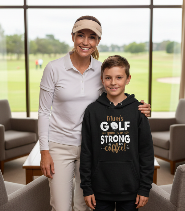 Woman and young boy standing together with a golf course in the background.  The boy is wearing a Cows Corner hoodie with a funny golf slogan 'Mum’s Golf Game Is As Strong as Her Coffee!'. Cows Corner gifts are perfect for sport-mad fans, these gifts work brilliantly for birthdays, new baby celebrations, Father’s Day, Mother’s Day, Christmas, anniversaries, thank you gifts, end-of-season team awards, graduations, retirements, and just-because moments when you want to raise a smile. 
