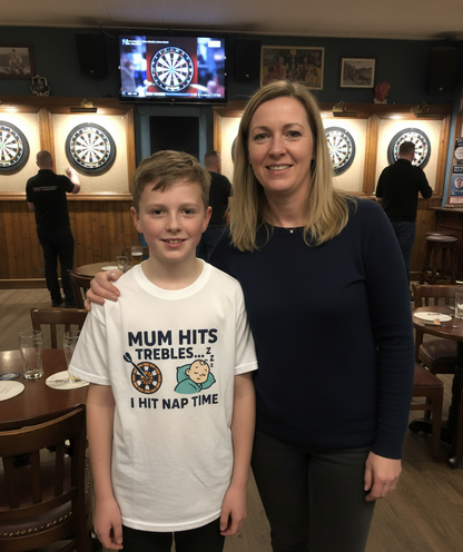 Woman and young boy standing together in a pub setting with dartboards on the wall.  The boy is wearing a Cows Corner t-shirt with the funny darts slogan that reads 'Mum Hits Trebles… I Hit Nap Time'.  Cows Corner gifts are perfect for sport-mad fans, these gifts work brilliantly for birthdays, new baby celebrations, Father’s Day, Mother’s Day, Christmas, anniversaries, thank you gifts, end-of-season team awards, graduations, retirements, and just-because moments when you want to raise a smile. 
