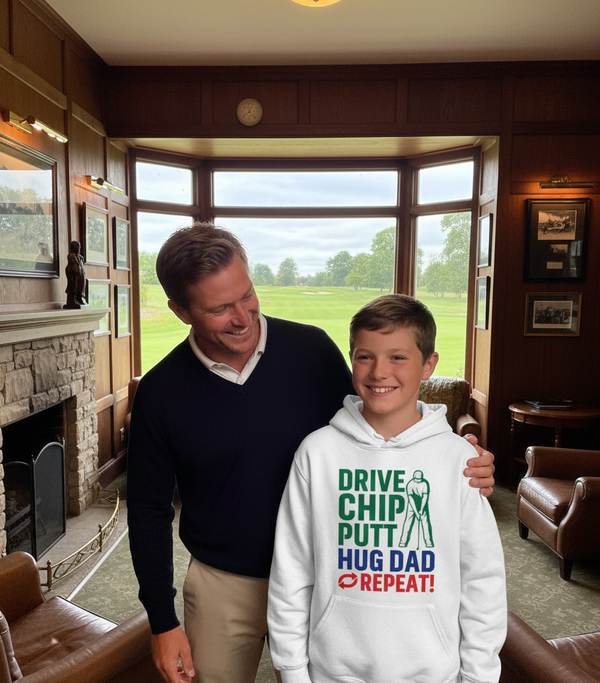 Man and young boy standing together in a room with large windows showing a green field. The boy is wearing a Cows Corner hoodie with a funny golf slogan 'Drive Chip Putt Hug Dad Repeat!'. Cows Corner gifts are perfect for sport-mad fans, these gifts work brilliantly for birthdays, new baby celebrations, Father’s Day, Mother’s Day, Christmas, anniversaries, thank you gifts, end-of-season team awards, graduations, retirements, and just-because moments when you want to raise a smile. 
