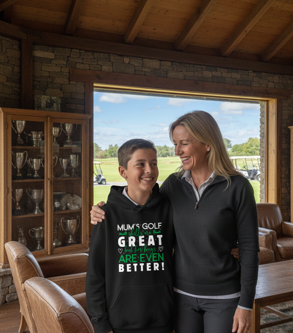 Woman and child standing in a room with a view of a golf course, wearing matching sweatshirts. The boy is wearing a Cows Corner hoodie with a funny golf slogan 'Mums Golf Skills Are Great but Her Hugs Are Even Better'. Cows Corner gifts are perfect for sport-mad fans, these gifts work brilliantly for birthdays, new baby celebrations, Father’s Day, Mother’s Day, Christmas, anniversaries, thank you gifts, end-of-season team awards, graduations, retirements, and just-because moments 
