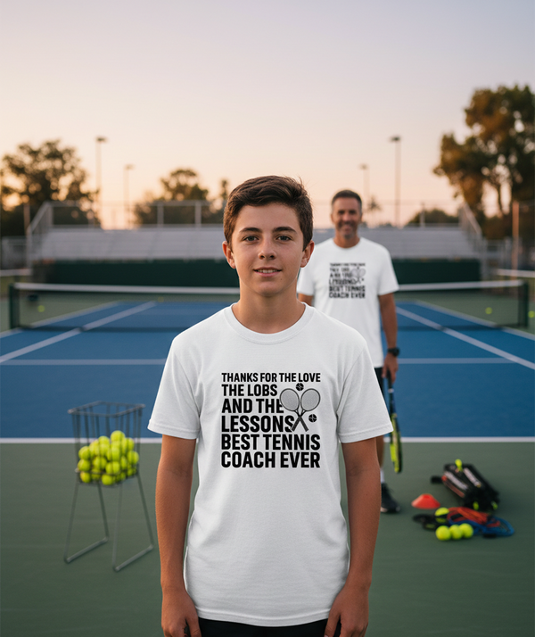 Two people on a tennis court with one wearing a white t-shirt with text. The boy is wearing a Cows Corner t-shirt with the funny tennis slogan 'Thanks for the Love the Lobs and the Lessons. Best Tennis Coach Ever'. Cows Corner gifts are perfect for sport-mad fans, these gifts work brilliantly for birthdays, new baby celebrations, Father’s Day, Mother’s Day, Christmas, anniversaries, thank you gifts, end-of-season team awards, graduations, retirements, and just-because moments when you want to raise a smile.
