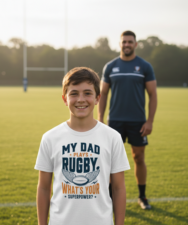 Young boy wearing a t-shirt with a rugby-themed message on a sports field. The boy is wearing a Cows Corner t-shirt with the funny rugby slogan 'My Dad Plays Rugby. What’s Your Superpower?'. Cows Corner gifts are perfect for sport-mad fans, these gifts work brilliantly for birthdays, new baby celebrations, Father’s Day, Mother’s Day, Christmas, anniversaries, thank you gifts, end-of-season team awards, graduations, retirements, and just-because moments when you want to raise a smile. 
