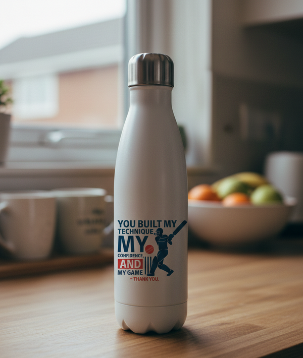 White water bottle with motivational quote on a kitchen counter. This is a Cows Corner water bottle with a funny cricket slogan 'You Built My Technique My Confidence and My Game – Thank You'. Cows Corner gifts are perfect for sport-mad fans, these gifts work brilliantly for birthdays, new baby celebrations, Father’s Day, Mother’s Day, Christmas, anniversaries, thank you gifts, end-of-season team awards, graduations, retirements, and just-because moments when you want to raise a smile. 
