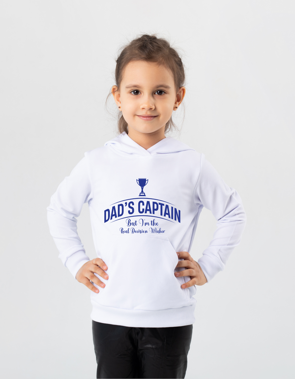 A little girl wearing a white hoodie with Dad's Captain, But I'm The Real Decision-Maker on the front. A Funny Cricket Hoodie, Premium Fabric, Multiple Junior Sizes, Perfect for Boys and Girls