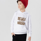 A little girl wearing a white hoodie with Dad’s Like a Spin Bowler, Always Full of Tricks on the front.  A Funny Cricket Hoodie, Premium Fabric, Multiple Junior Sizes, Perfect for Boys and Girls