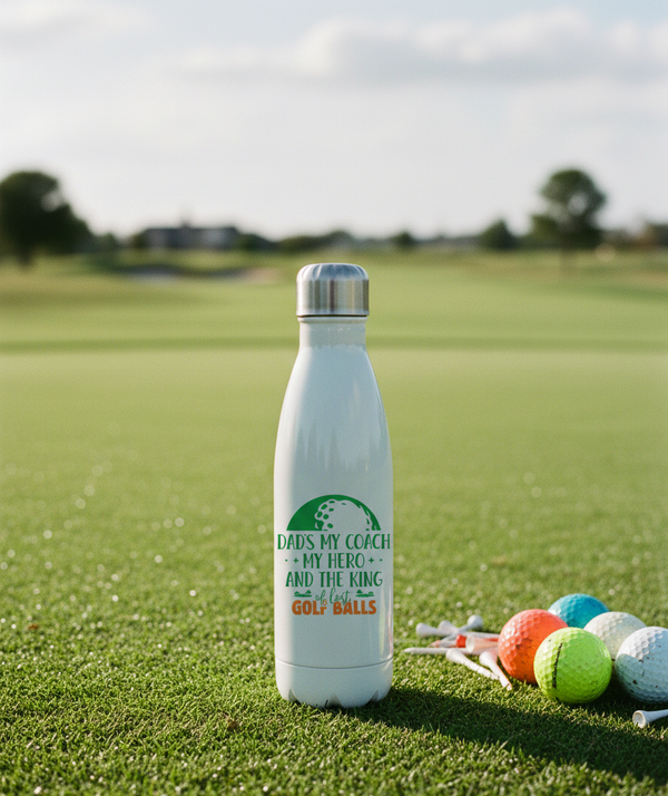 White water bottle with a humorous message on a golf course. This is a Cows Corner water bottle with a funny golf slogan 'Dads My Coach, My Hero and the King of Lost Golf Balls'. Cows Corner gifts are perfect for sport-mad fans, these gifts work brilliantly for birthdays, new baby celebrations, Father’s Day, Mother’s Day, Christmas, anniversaries, thank you gifts, end-of-season team awards, graduations, retirements, and just-because moments when you want to raise a smile. 
