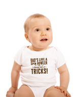 A baby wearing a baby grow with Dads Like a Spin Bowler, Always Full of Tricks, on the front! Funny Cricket Baby Bodysuit, Organic or In-Conversion to Organic Cotton, Self Fabric Bound Neckline, Cuffs and Leg Openings