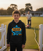 Child wearing a hoodie with a cricket-themed design on a grassy field. The boy is wearing a Cows Corner hoodie with the funny cricket slogan 'Dad is a Great Fielder, Always Catching Me Out'. Cows Corner gifts are perfect for sport-mad fans, these gifts work brilliantly for birthdays, new baby celebrations, Father’s Day, Mother’s Day, Christmas, anniversaries, thank you gifts, end-of-season team awards, graduations, retirements, and just-because moments when you want to raise a smile. 
