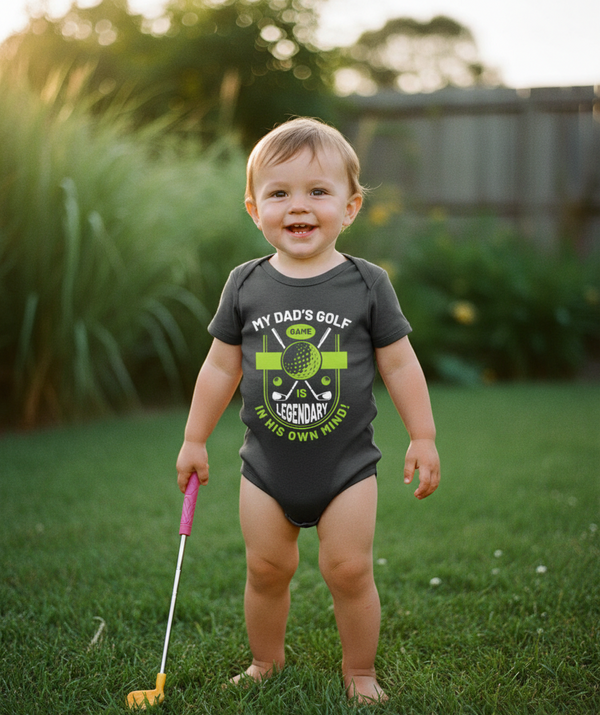 Child wearing a onesie with a golf-themed design outdoors on grass. The baby is wearing a Cows Corner baby grow with the funny golf slogan 'My Dad’s Golf Game Is Legendary in His Own Mind!'. Cows Corner gifts are perfect for sport-mad fans, these gifts work brilliantly for birthdays, new baby celebrations, Father’s Day, Mother’s Day, Christmas, anniversaries, thank you gifts, end-of-season team awards, graduations, retirements, and just-because moments when you want to raise a smile. 
