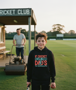 Boy wearing a hoodie with a cricket-themed message on a cricket field, with a man operating a lawn mower in the background. The boy is wearing a Cows Corner hoodie with the funny cricket slogan 'If Cricket Is Life, Then Dad's The Groundkeeper'. Cows Corner gifts are perfect for sport-mad fans, these gifts work brilliantly for birthdays, new baby celebrations, Father’s Day, Mother’s Day, Christmas, anniversaries, thank you gifts, end-of-season team awards, graduations, retirements, and just-because moments