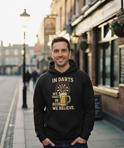 Man wearing a black hoodie with a darts and beer graphic and text on a street. The man is wearing a Cows Corner hoodie with the funny darts slogan 'In Darts We Trust, in Beer We Believe'. Cows Corner gifts are perfect for sport-mad fans, these gifts work brilliantly for birthdays, new baby celebrations, Father’s Day, Mother’s Day, Christmas, anniversaries, thank you gifts, end-of-season team awards, graduations, retirements, and just-because moments when you want to raise a smile. 
