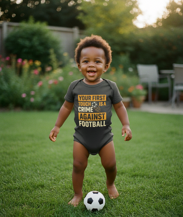 Child wearing a humorous soccer-themed onesie in a garden setting. The baby is wearing a Cows Corner baby grow with a funny football slogan 'Your First Touch Is a Crime Against Football'. Cows Corner gifts are perfect for sport-mad fans, these gifts work brilliantly for birthdays, new baby celebrations, Father’s Day, Mother’s Day, Christmas, anniversaries, thank you gifts, end-of-season team awards, graduations, retirements, and just-because moments when you want to raise a smile. 
