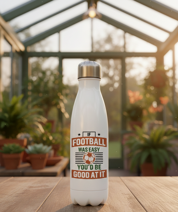 White water bottle with a football-themed design in a greenhouse setting. This is a Cows Corner water bottle with a funny football slogan 'If Football Was Easy You’d Be Good at It'. Cows Corner gifts are perfect for sport-mad fans, these gifts work brilliantly for birthdays, new baby celebrations, Father’s Day, Mother’s Day, Christmas, anniversaries, thank you gifts, end-of-season team awards, graduations, retirements, and just-because moments when you want to raise a smile. 
