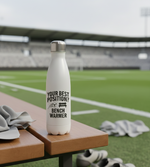 White water bottle with text on a sports field. Cows Corner funny birthday present water bottle with funny slogan 'your best position?  Bench warmer!  Cows Corner gifts are perfect for sport-mad fans, these gifts work brilliantly for birthdays, new baby celebrations, Father’s Day, Mother’s Day, Christmas, anniversaries, thank you gifts, end-of-season team awards, graduations, retirements, and just-because moments when you want to raise a smile. 