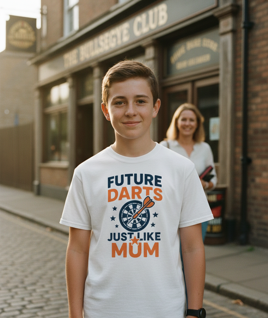 Young boy wearing a t-shirt with 'Future Darts Just Like Mum' text in an urban setting. A Cows Corner t-shirt with the funny darts slogan 'Future Darts Star Just Like Mum'. Cows Corner gifts are perfect for sport-mad fans, these gifts work brilliantly for birthdays, new baby celebrations, Father’s Day, Mother’s Day, Christmas, anniversaries, thank you gifts, end-of-season team awards, graduations, retirements, and just-because moments when you want to raise a smile. 
